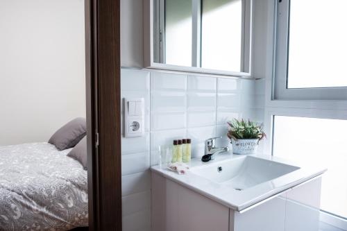 une salle de bain avec un lavabo et un lit dans l'établissement Hotel Bienvenidos Rooms Xàtiva, à Xàtiva
