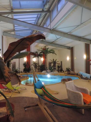 a room with a pool with a hammock and chairs at Résidence Beauvoir le Mont-Saint-Michel (9 gîtes de 2 à 5 personnes) in Beauvoir