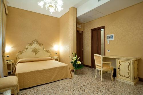 a bedroom with a bed and a desk and a chair at Hotel Al Malcanton in Venice