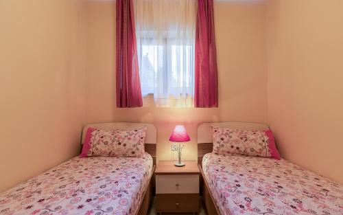 2 aparte bedden in een kleine kamer met een raam bij Apartmani Kažun - App1 in Fažana