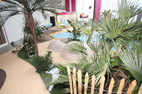 an indoor garden with palm trees and a pool at Résidence Beauvoir le Mont-Saint-Michel (9 gîtes de 2 à 5 personnes) in Beauvoir