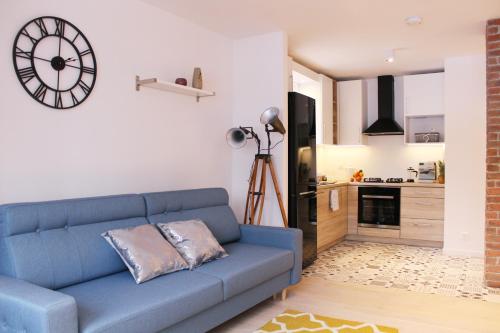 ein Wohnzimmer mit einem blauen Sofa und einer Küche in der Unterkunft Comfy with great city view by Cooee Apartments in Warschau