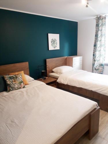 1 dormitorio con 2 camas y pared azul en Pokoje Gościnne Plażowa, en Białystok