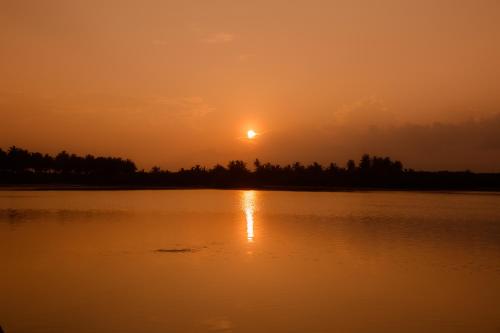a sunset over a large body of water at Equator Village Maldives in Gan