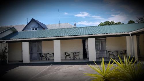 a group of chairs sitting on the porch of a house at Chanel Court Motel in Masterton