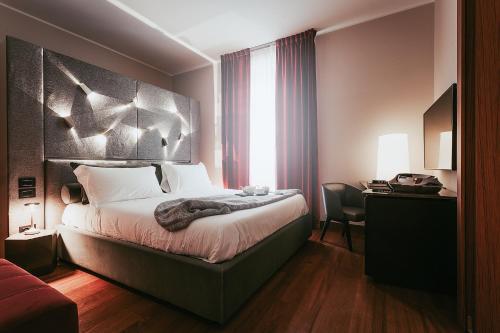 a hotel room with a large bed and a desk at Bacã Suites, Restaurant & Bar in Taranto