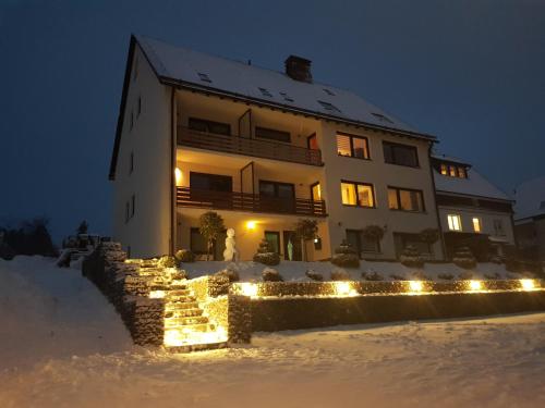 un bâtiment avec des lumières dans la neige la nuit dans l'établissement Blissberg Winterberg, à Winterberg