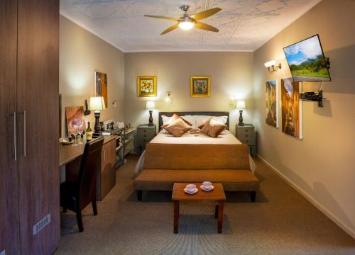 1 dormitorio con cama, escritorio y mesa en Forest Hall Guest House, en Port Elizabeth