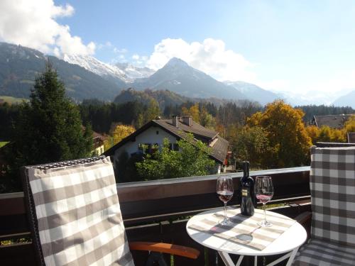 a table with wine glasses on a balcony with mountains at Ferienwohnungen im Färberhaus in Fischen