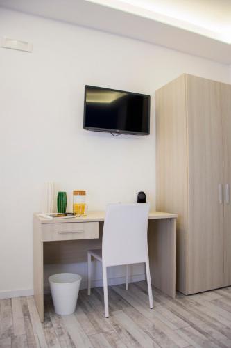 a desk with a white chair and a tv on a wall at B&b '900 in Foggia