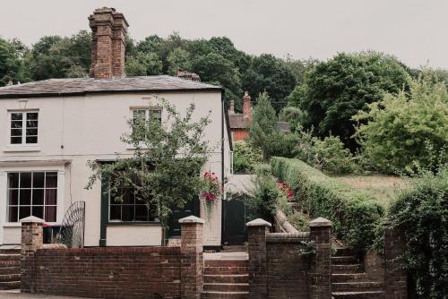 a white house with a brick fence in front of it at Penny Black Cottage in Coalbrookdale
