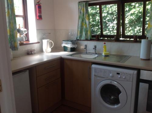 a kitchen with a washing machine and a sink at New Stable Cottage in Cowes