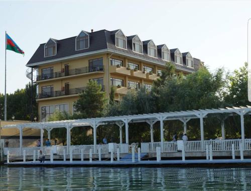 a large building on the water in front of a building at River Side Hotel in Mingachevir