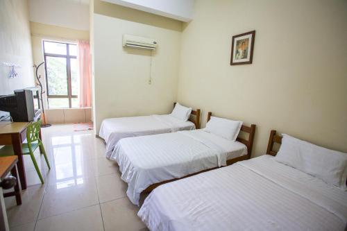 a room with three beds and a desk and a television at Hotel Comfort Inn in Kluang