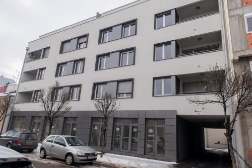 een wit gebouw met auto's ervoor geparkeerd bij Apartmani Hemera in Valjevo