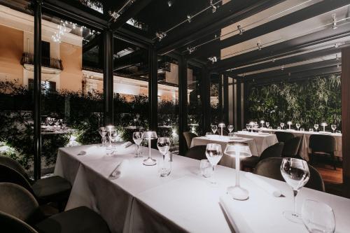 a restaurant with white tables and chairs with wine glasses at Bacã Suites, Restaurant & Bar in Taranto
