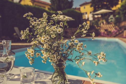 a vase of flowers on a table next to a pool at Agriturismo I Surì Asti in Asti