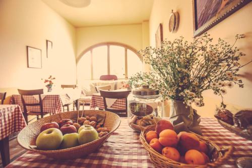 a table with two baskets of fruit and a vase of flowers at Agriturismo I Surì Asti in Asti