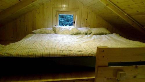 a large bed in a wooden room with a window at Acapulco Domki Radków in Wünschelburg