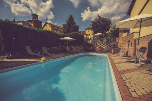 a large blue swimming pool with chairs and umbrellas at Agriturismo I Surì Asti in Asti