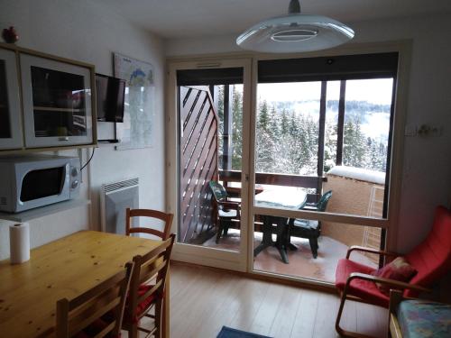 a living room with a dining room table and a balcony at Les Brettaz in Bellevaux