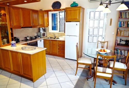 a kitchen with a table and a white refrigerator at Villa Marika in Vathi, Ithaka