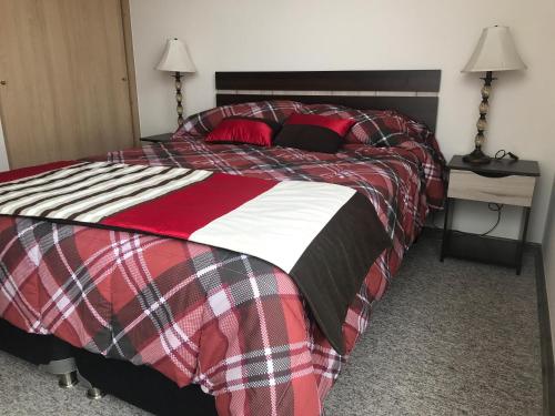 een slaapkamer met een bed met een rode en zwarte deken bij Horizonte infinito in Viña del Mar
