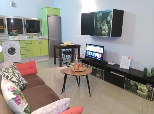 a living room with a couch and a tv and a kitchen at Loft LUMINOSO San Juan in Telde