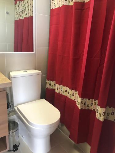 a bathroom with a toilet and a red shower curtain at Horizonte infinito in Viña del Mar