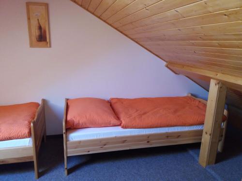 two beds with orange pillows in a room at Penzion Ve Staré škole in Vlastějovice