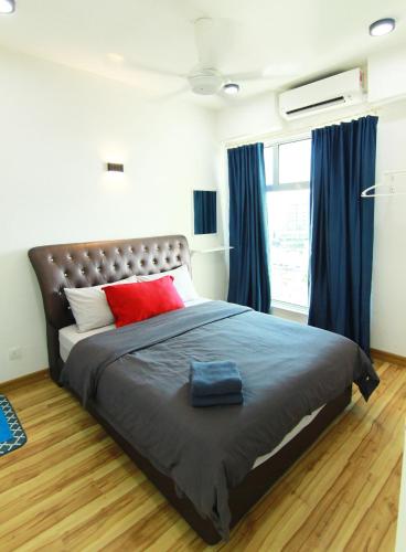 a bedroom with a large bed with red pillows and blue curtains at 10:39 Studio @ D'Perdana Sri Cemerlang in Kota Bharu
