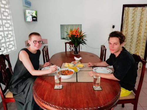a man and woman sitting at a table eating food at Old Parkland Hostel in Galle
