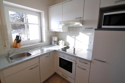 a kitchen with white cabinets and a sink and a window at Dünenhaus in Göhren