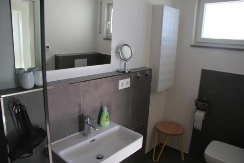 La salle de bains est pourvue d'un lavabo, d'un miroir et d'un tabouret. dans l'établissement Ferienwohnung no.55, à Lörrach