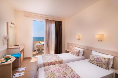 um quarto de hotel com duas camas e vista para o oceano em Sunray Hotel em Limenaria