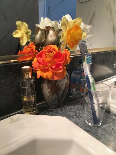 a vase with flowers sitting on a bathroom sink at Bed & Breakfast Rita in Delfzijl