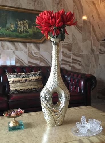 a silver vase with a red flower in it on a table at Bed & Breakfast Rita in Delfzijl