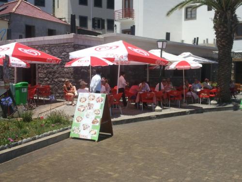 a restaurant with red umbrellas and people sitting at tables at Hotel Costa Linda in Porto da Cruz