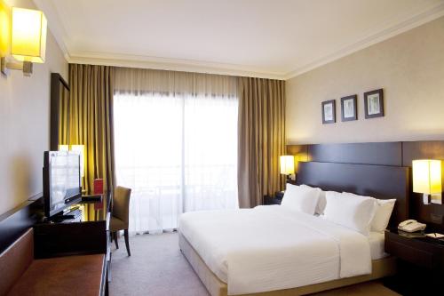 a hotel room with a large bed and a television at Ramada Plaza by Wyndham Beirut Raouche in Beirut