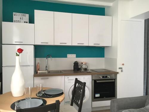 a kitchen with white cabinets and a wooden table at SWEET APARTMENT CARRIERES - 1 chambre - 4 Pers - Wifi in Carrières-sur-Seine
