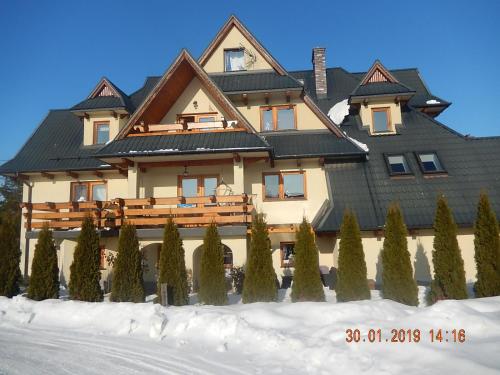 a large house with a black roof in the snow at U Hanki in Biały Dunajec