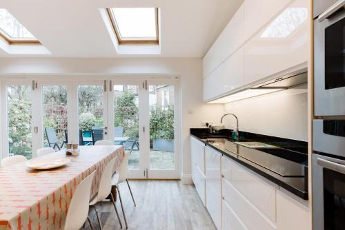 a kitchen with white cabinets and a long table with chairs at Tadmor Townhouse in London