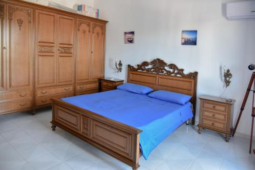 a bedroom with a bed with blue sheets and wooden cabinets at Villa Mary in Torre Lapillo