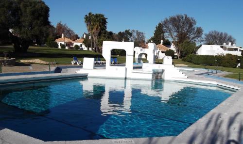 a swimming pool with blue water in a yard at Pedras D'el Rei Waterfront Loft in Tavira