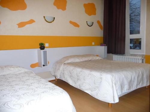 a bedroom with two beds and a yellow wall at Hotel Alain et Martine in Viviers-du-Lac