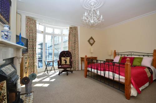 a bedroom with a bed and a chair and a chandelier at Casa Mar Bella, a Large House with Sweeping Sea and Beach Views in Ramsgate