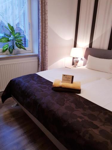 a hotel room with a bed with a book on it at Hotel garni Morsum in Nordstrand