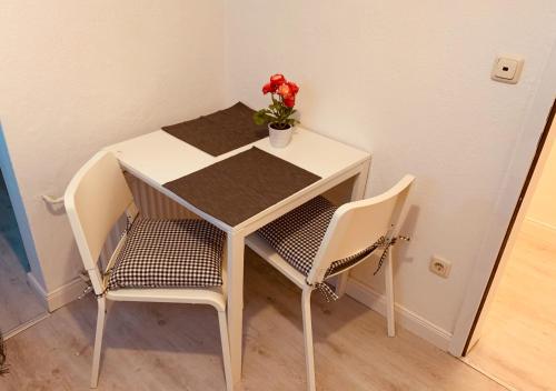 stół z dwoma krzesłami i wazon z kwiatem w obiekcie A2-Bremen an der Weser w Bremie