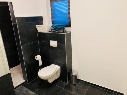 Łazienka z toaletą w pokoju wyłożonym czarnymi kafelkami w obiekcie A2-Bremen an der Weser w Bremie