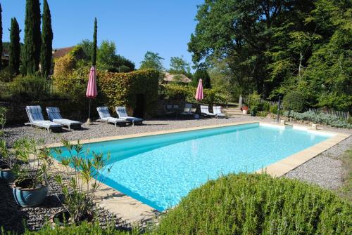 une piscine avec chaises et parasols dans une cour dans l'établissement Domaine de la Charmeraie Piscine chauffée, à Saint-Cirq